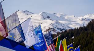 View of snowy mountains with flags in the foreground at Davos in 2025